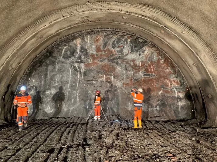 Bauarbeiter stehen vor der Tunnelwand