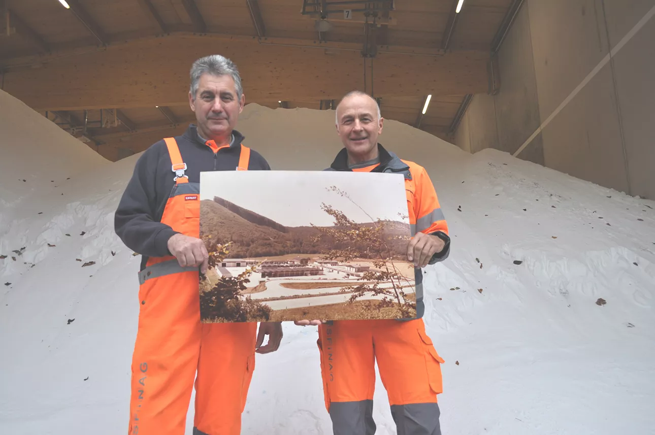Anton Vogl und Josef Kummer stehen vor einem Haufen Salz und halten ein altes Foto der ABM Alland