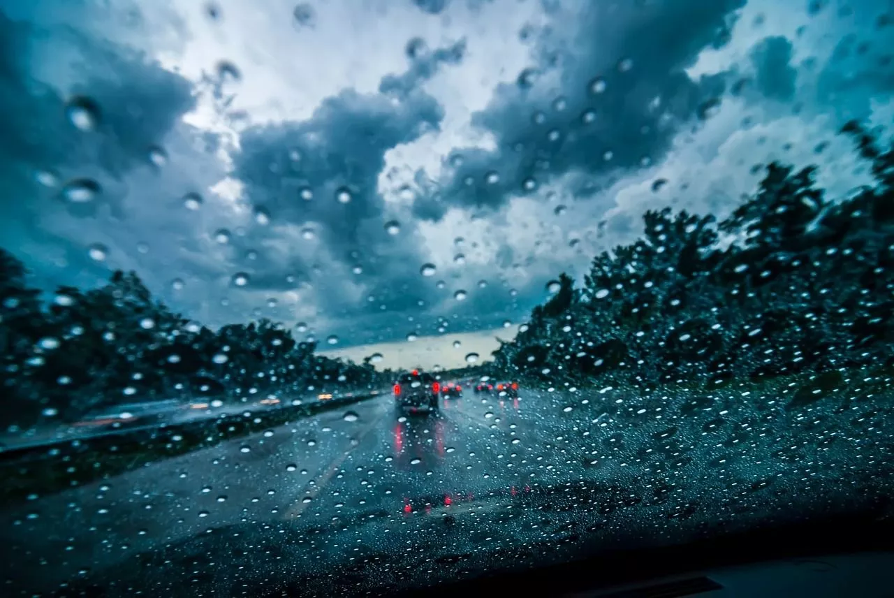 Blick auf die Autobahn durch eine Windschutzscheibe mit Regentropfen darauf