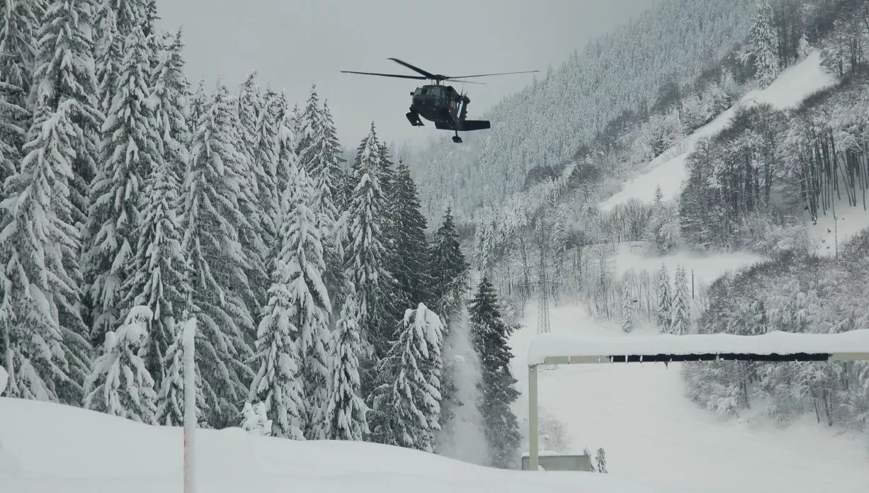 Ein schwarzer Hubschrauber fliegt über eine verschneite Landschaft