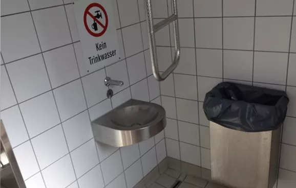 Zugang zum Waschbecken in einem Behinderten-WC durch einen fixmontierten Mülleimer verstellt