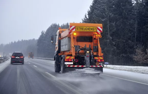 Winterdienstfahrzeug streut Salz auf die Autobahn