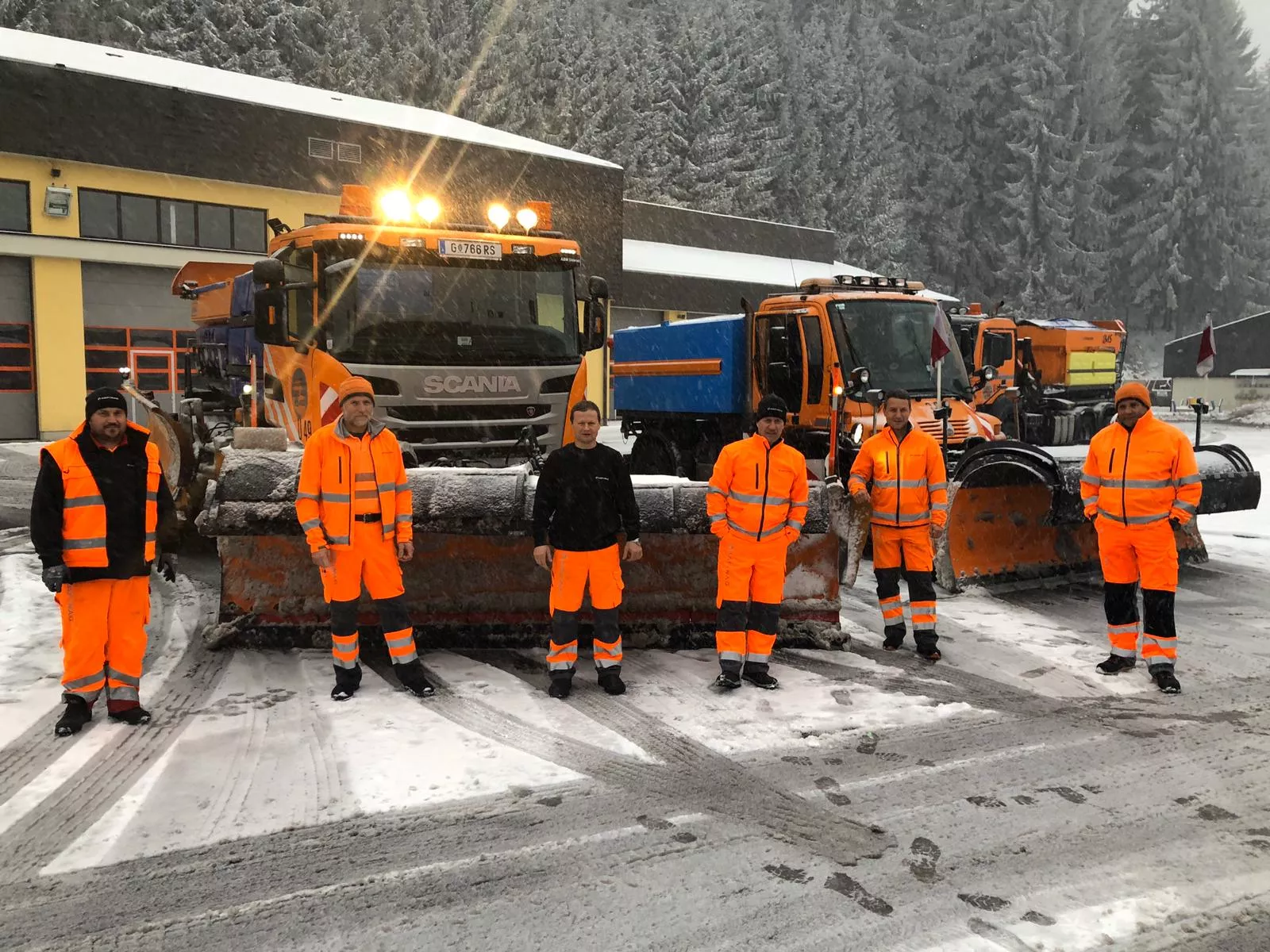 Unsere Mitarbeiter vor den Winterdienstfahrzeugen. In unseren Autobahnmeistereien gelten strenge Hygienemaßnahmen.