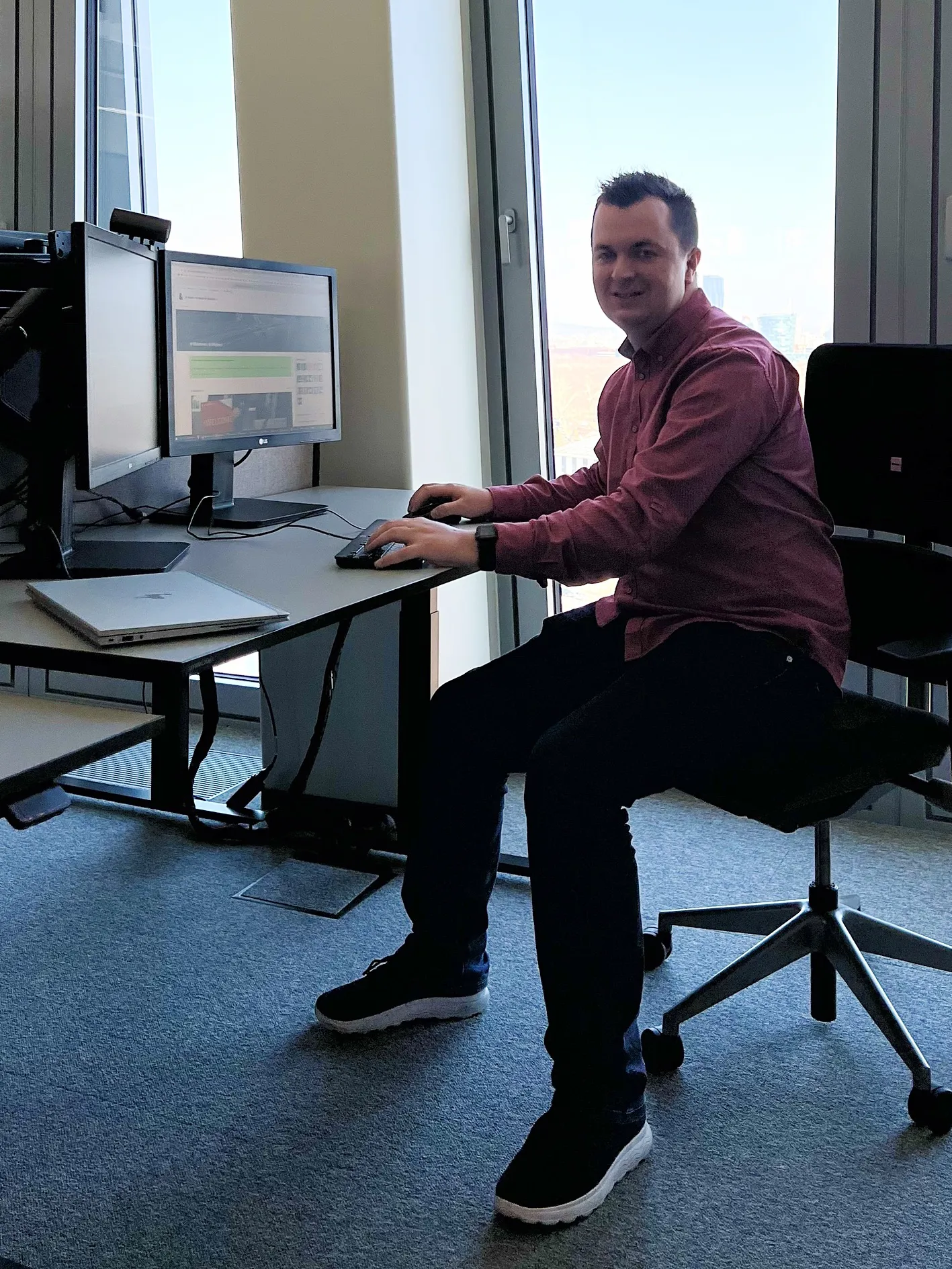 Ein Mann sitzt ein einem Schreibtisch vor zwei Bildschrimen