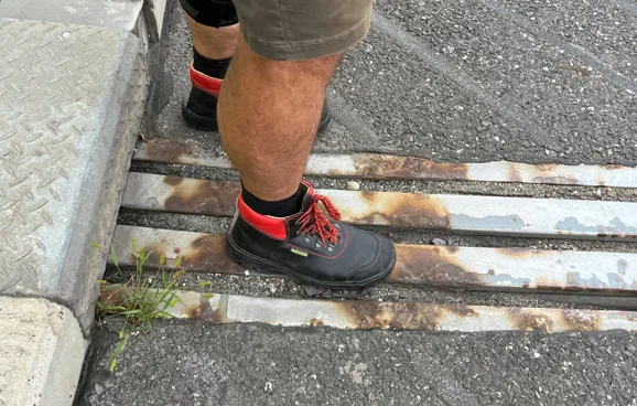 Blick von oben auf die Füße von Fritz, der mit den Füßen auf der Dehnungsfuge steht.