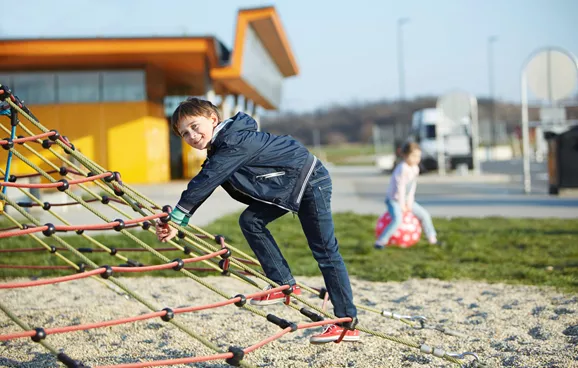 Ein Kind klettert auf einem Netz auf einem ASFINAG Rastplatz Kinderspielplatz