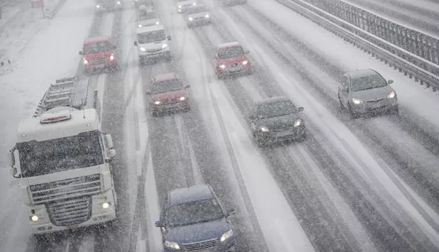 4-spurige verschneite Autobahn, auf der sich die schwarzen Fahrspuren abzeichnen