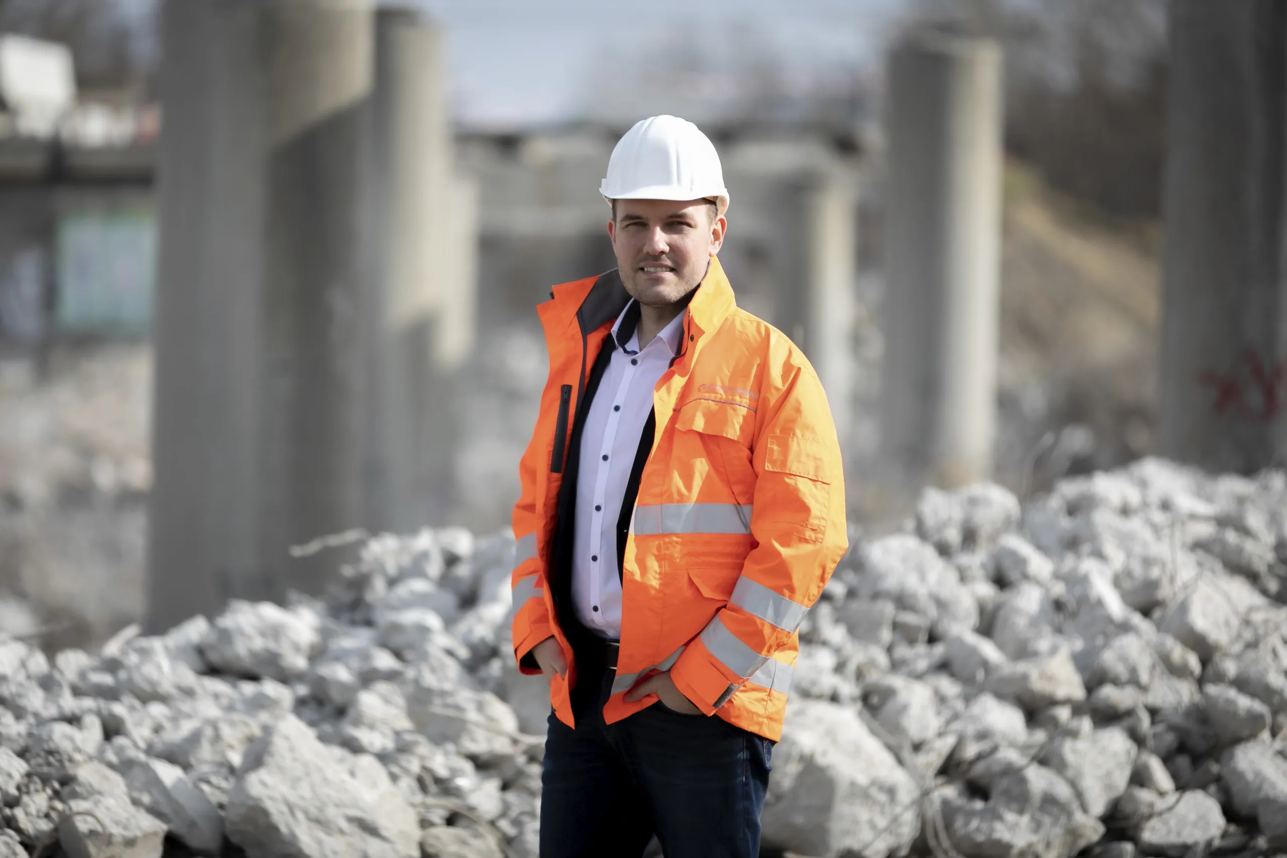 Ein Mann in Warnweste und Harthelm vor Geröll