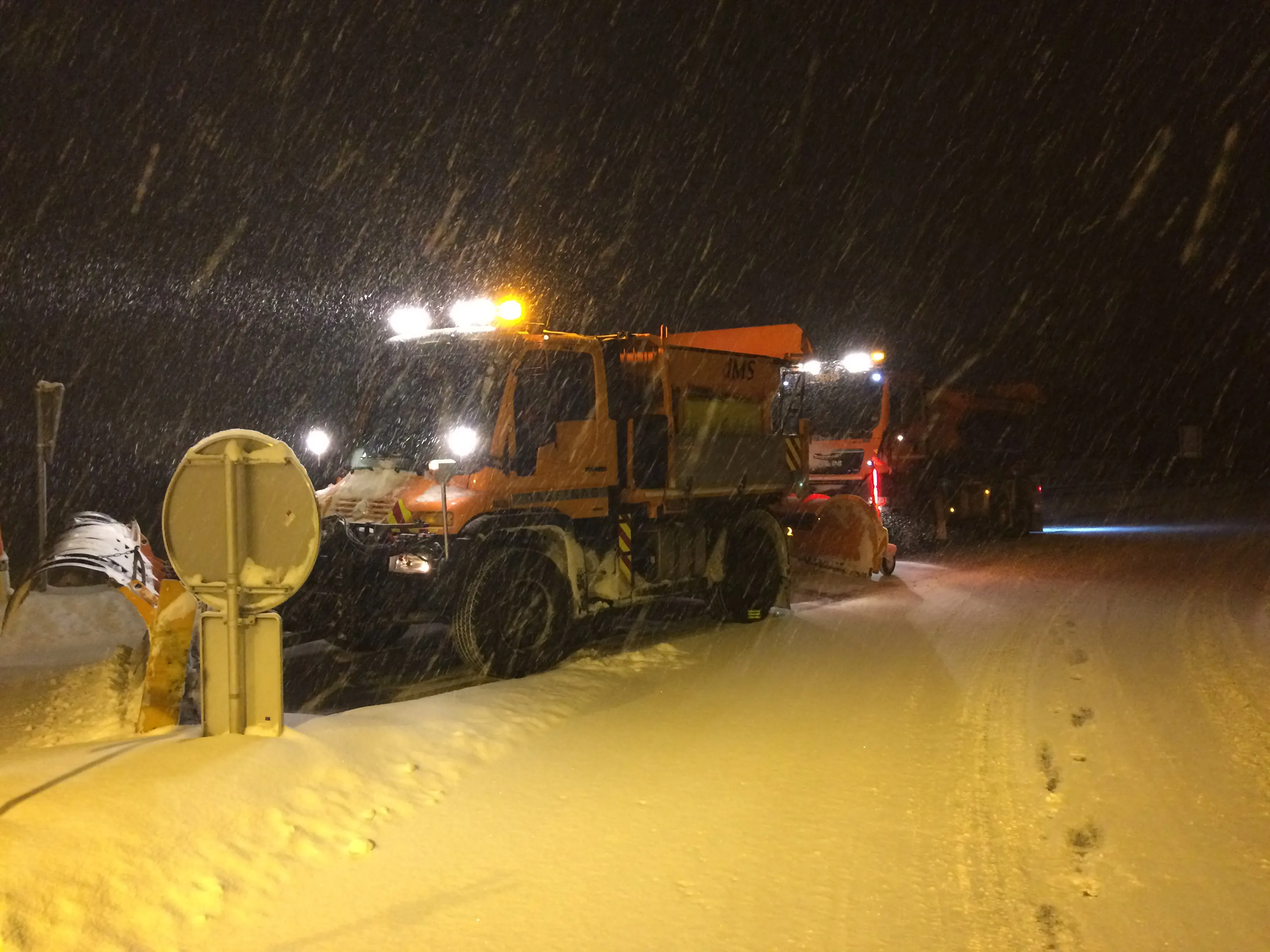 Unimog und Lkw im Schnee bei Nacht