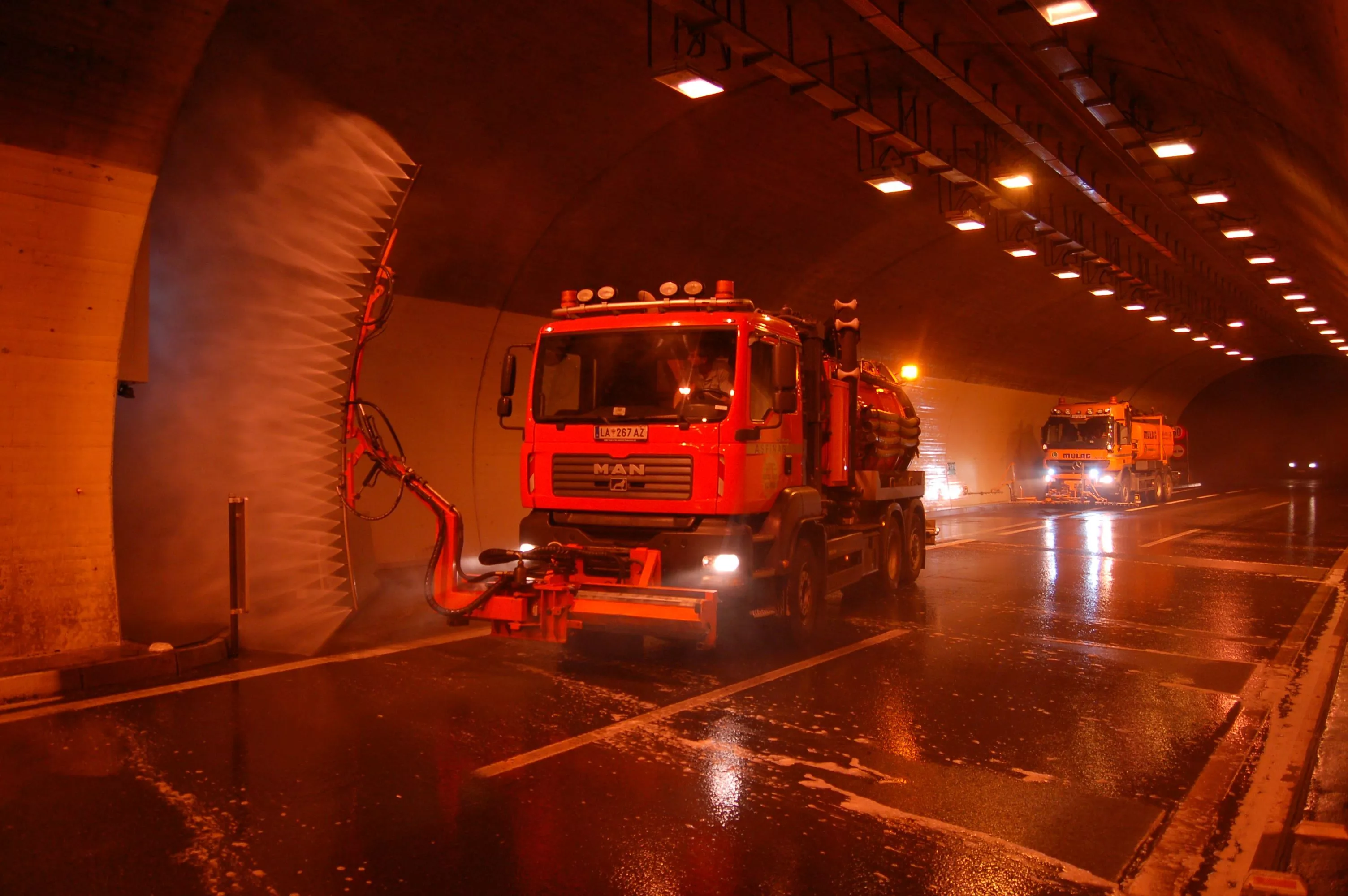 Ein Lkw fährt durch einen Tunnel und besprüht die Tunnelwand mit Wasser