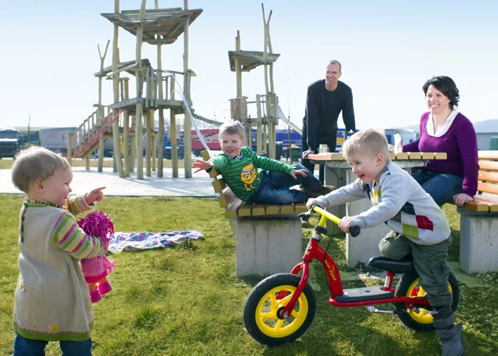 Ein Mann, eine Frau und drei kleine Kinder auf einem Rastplatz-Spielplatz