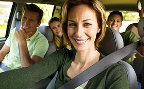 Ein Selfie einer Frau. Mit ihr im Auto sind ein Mann und zwei Kinder.