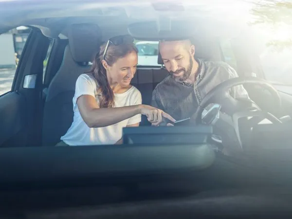 Mann und Frau sitzen im Auto und besprechen die Route.