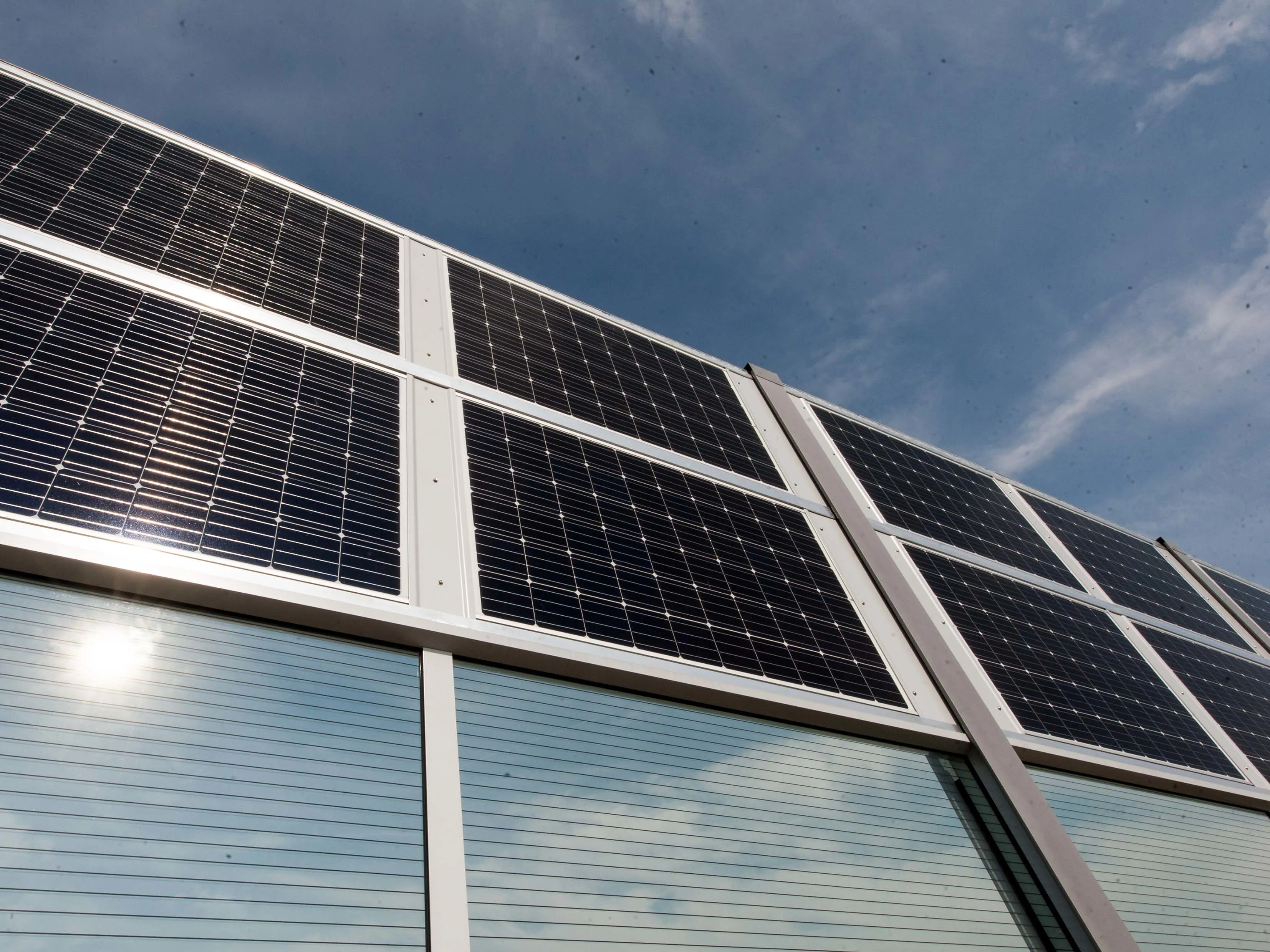 Man sieht eine Lärmschutzwand, die unten transparent ist und oben PV-Paneele trägt. (Quelle: R. Kohlhauer GmbH)